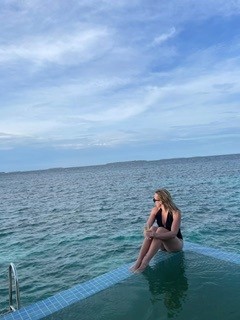 Kvinna sitter på en brygga och blickar ut över havet